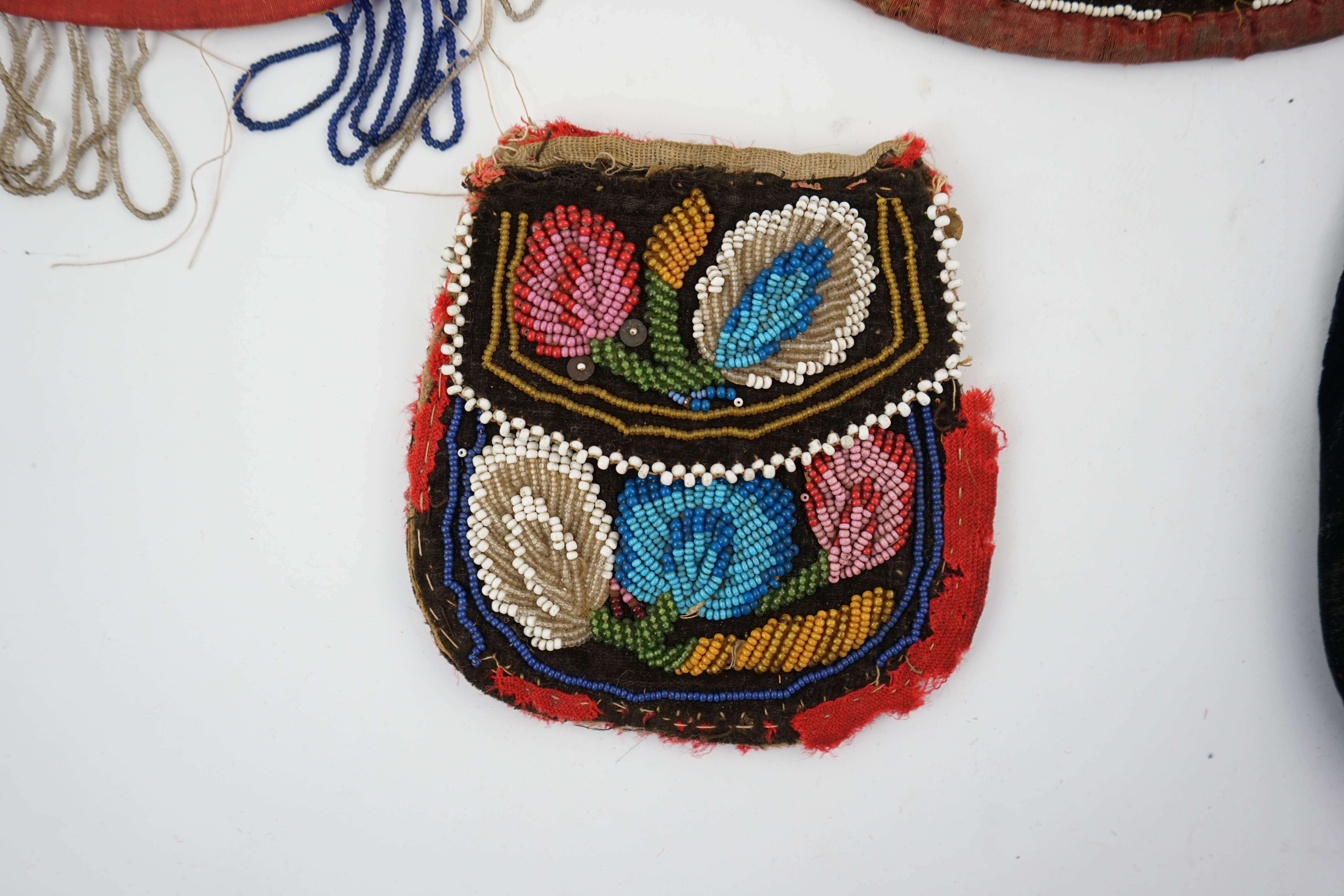 Four 19th century Iroquois Native American beaded bags, three large and one smaller, all bags worked in various colours and differing designs, all with flaps and same pattern both sides, largest 19cm high. Condition - al